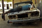 rapaz sobre carro velho na ilha de Moçambique