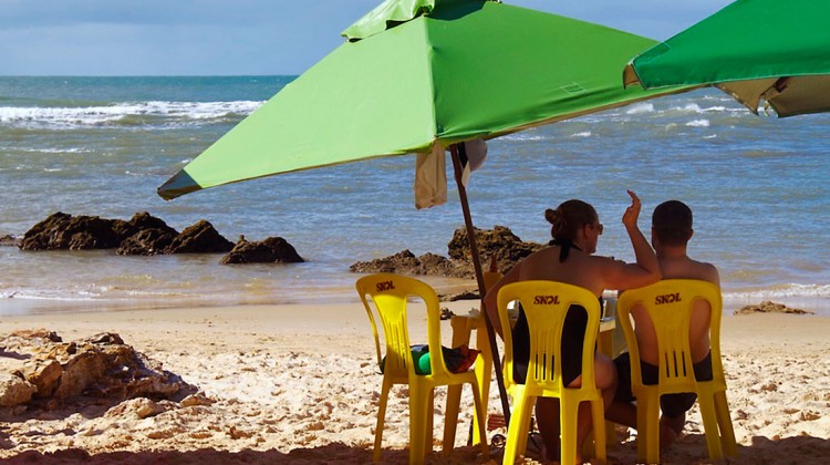 casal sob chapéus de sol, sentado em cadeiras de plástico, no morro são paulo, brasil