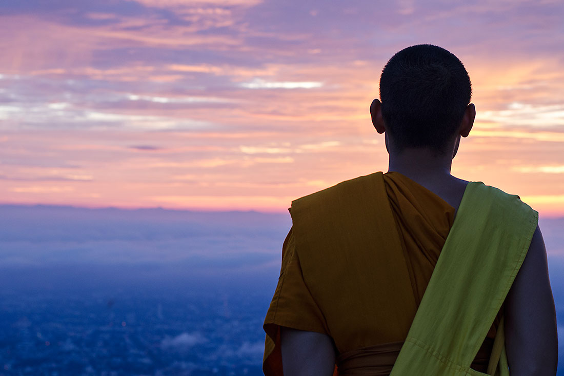 monge budista que observa o pôr-do-sol