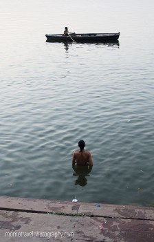 barco que passa no ganges e homem a fazer a sua puja