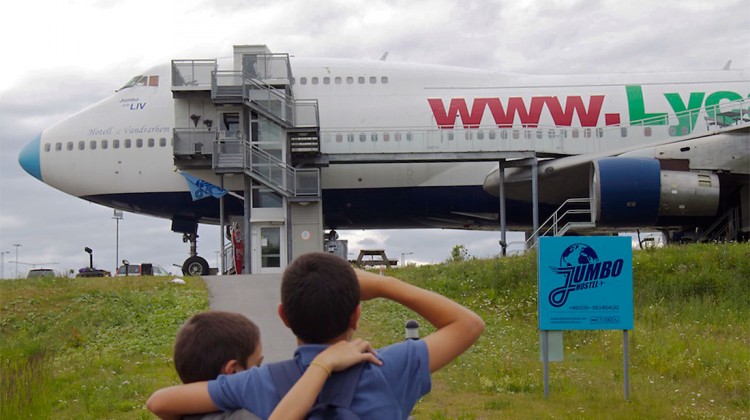 crianças junto à entrada do jumbo stay, um avião transformado em hostel