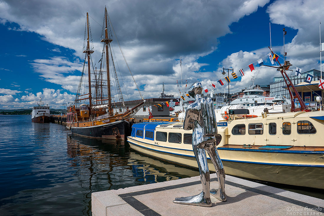 estátua de mergulhador e barcos no cais maritimo de Oslo