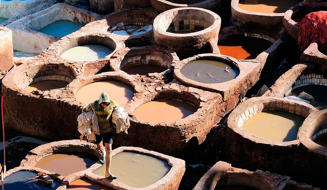 homem que caminha sobre bordas dos tanques de tingimento de curtumes na cidade de Fez