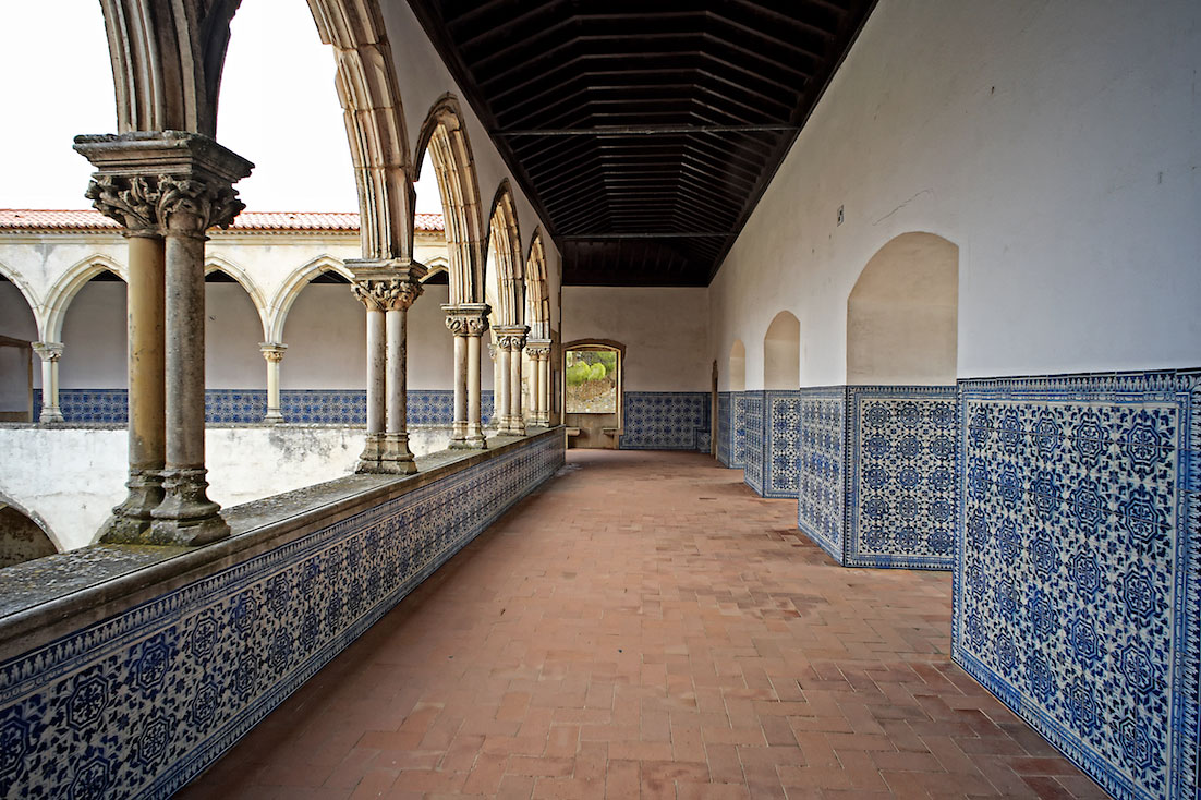 Corredores com paredes forradas a azulejo que ladeiam o primeiro piso de um dos claustros