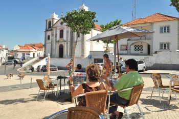 Pessoas numa esplanada junto à igreja em Palmela.