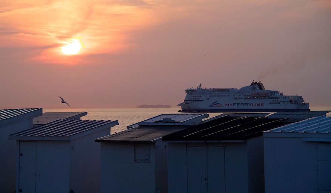 ferry e barracas de praia ao pôr-do-sol na cidade de Calais, em França.