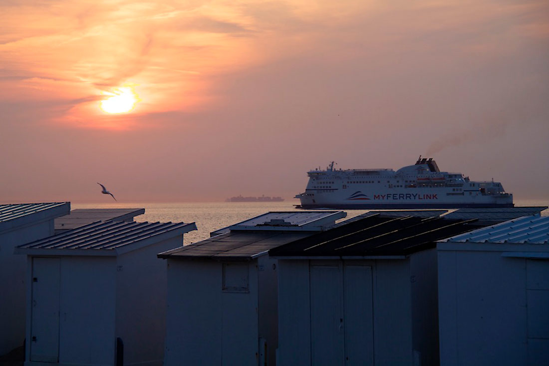 ferry e barracas de praia ao pôr-do-sol na cidade de Calais, em França.