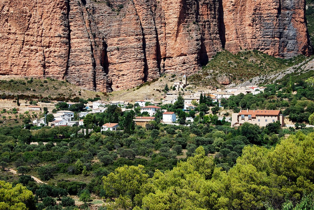 Aldeia de Riglos por entre vegetação serrada e a parede de um Mallo