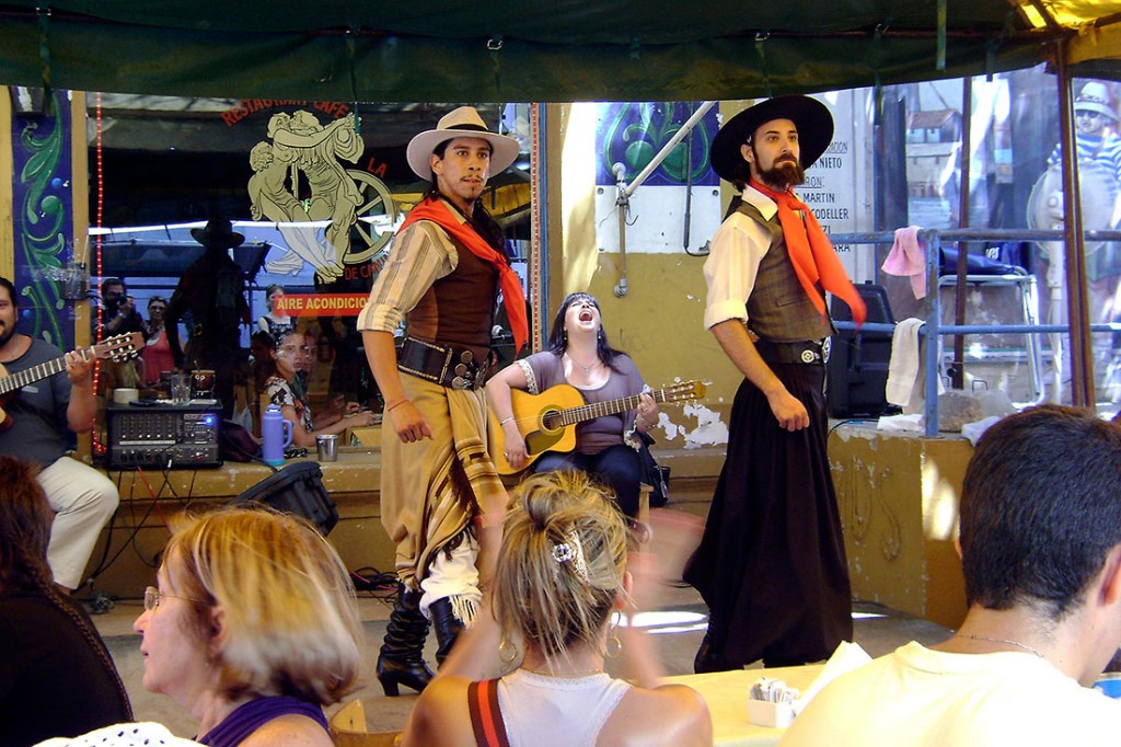 Grupo de dançarinos e músicos que actuam para o público num bar del Caminito em Buenos Aires