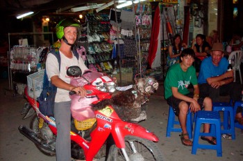homem a conduzir moto com cachorro no certo frontal na noite de Banguecoque