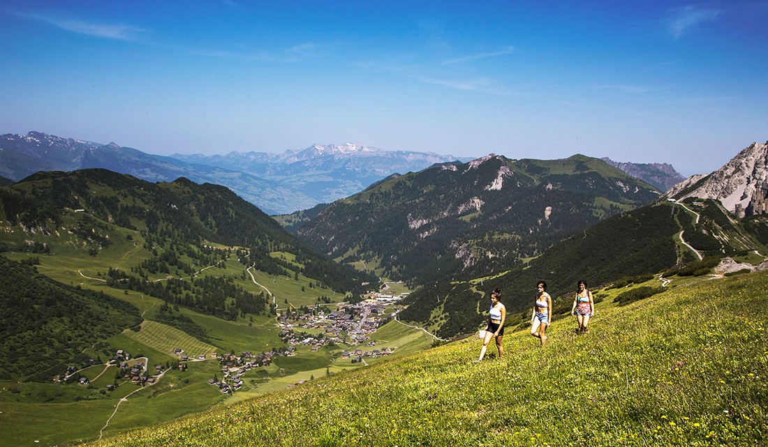 mulheres num trekking nas montanhas do liechtenstein, com vista para uma aldeia no vale