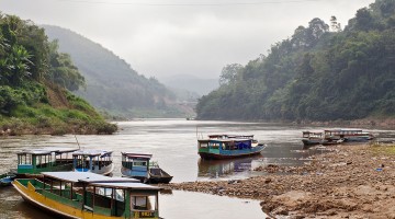Barcos com várias cores na margem do rio Nam Ou, junto à aldeia Muang Ngoi Neua, no Laos.