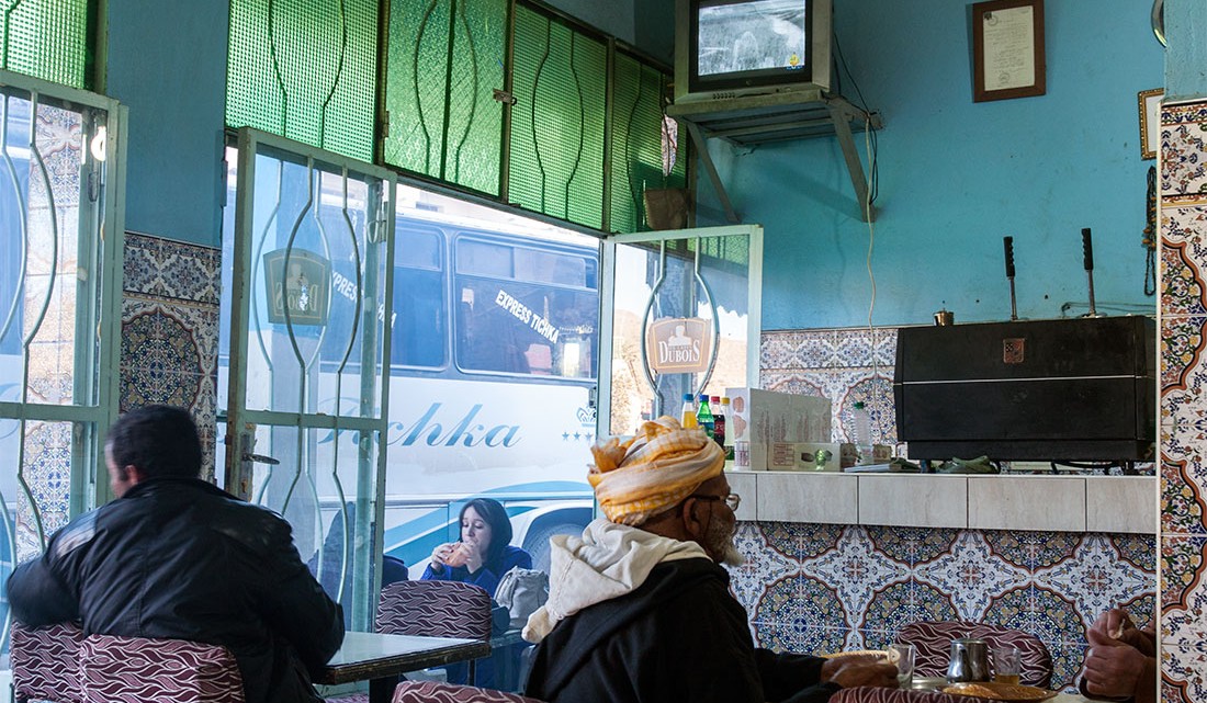 Pessoas num café central de paredes revestidas a azulejo algures na estada que atravessa o Atlas marroquino.