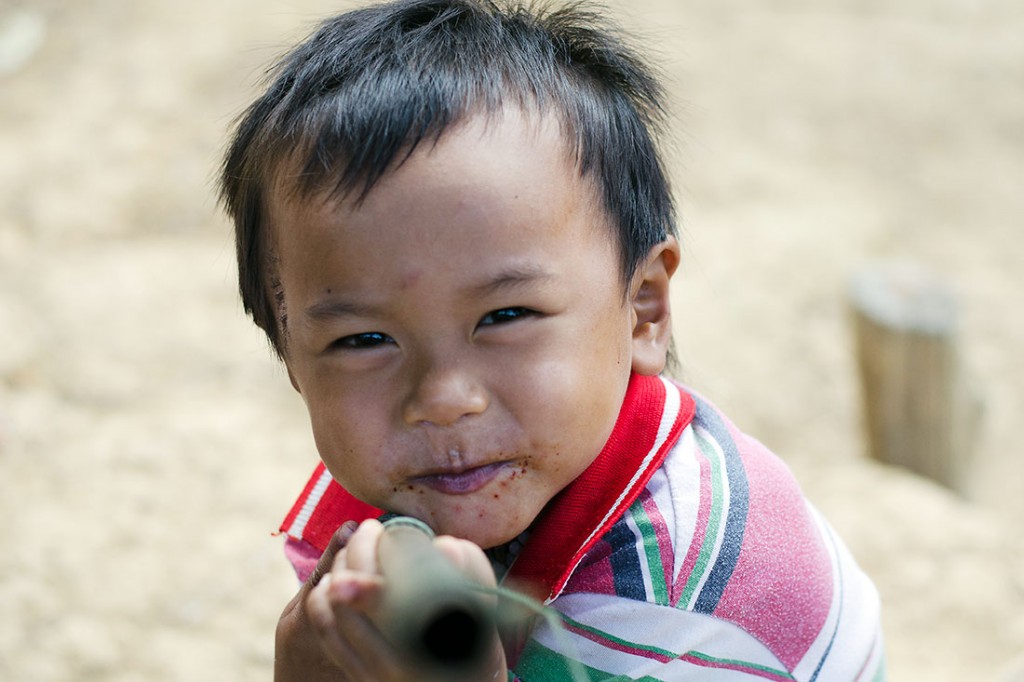 Criança a brincar com cana na aldeia de Muang Nngoi Neua.