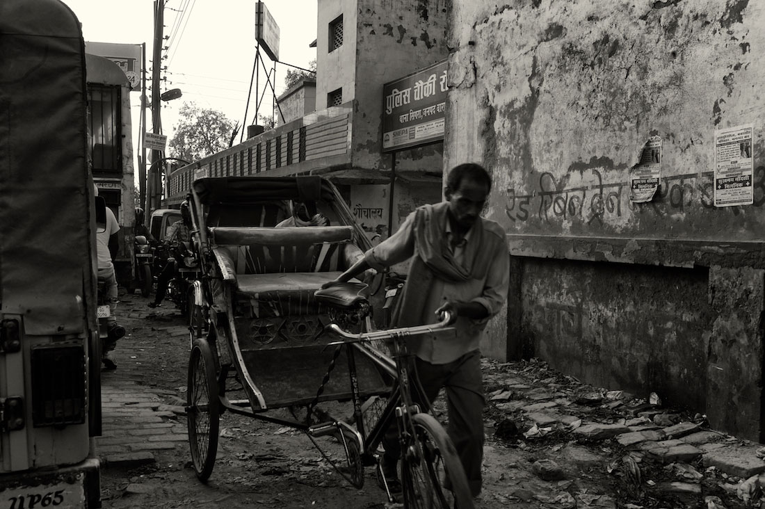 Homem a puxar rickshaw versão bicicleta na Índia.