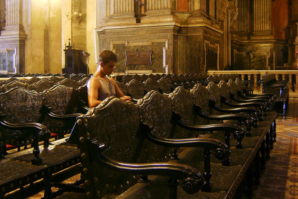 Rapaz sentado nos grandes cadeirões do interior da igreja da candelária no Rio de Janeiro.