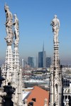 Edifícios modernos da cidade de Milão por entre as esculturas do terraço da catedral Duomo