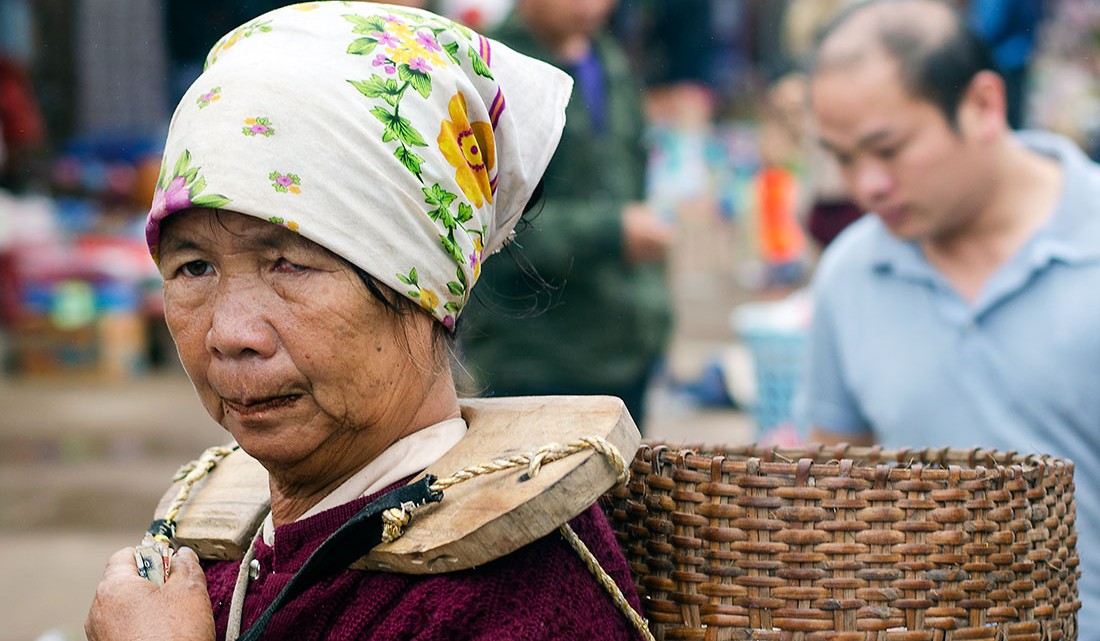 Mulher a carregar um cesto no mercado de Muang Sing.