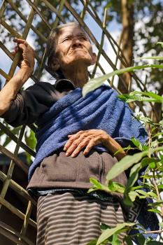 Mulher idosa junto a vedação de madeira na aldeia de Muang Ngoi Neua.