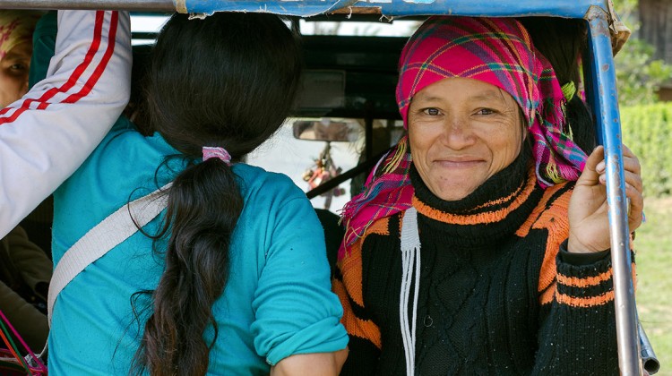 Várias mulheres transportadas nas traseiras de um tuk-tuk numa estrada do Laos.