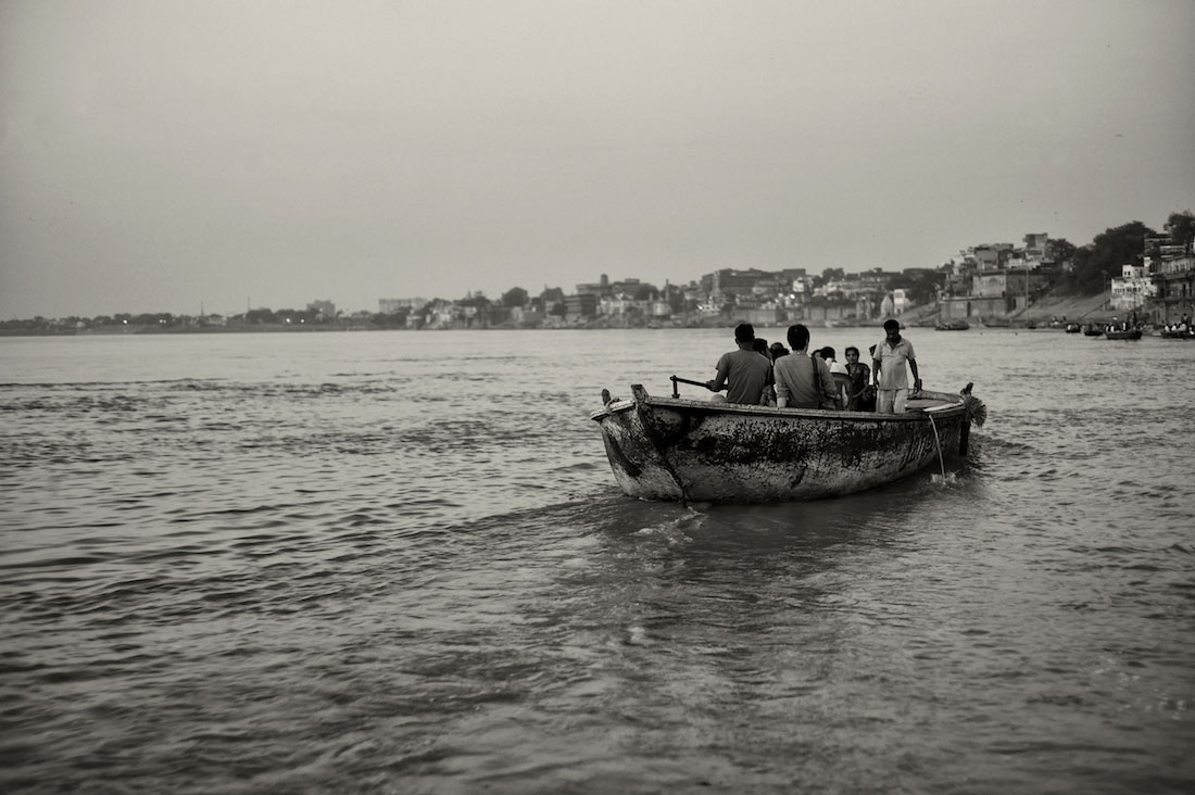 Pequeno barco com indianos a navegar nas águas do rio Ganges em Varanasi.