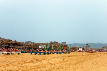 Areal e cabanas de palha na praia em Candolim, norte de Goa, Índia