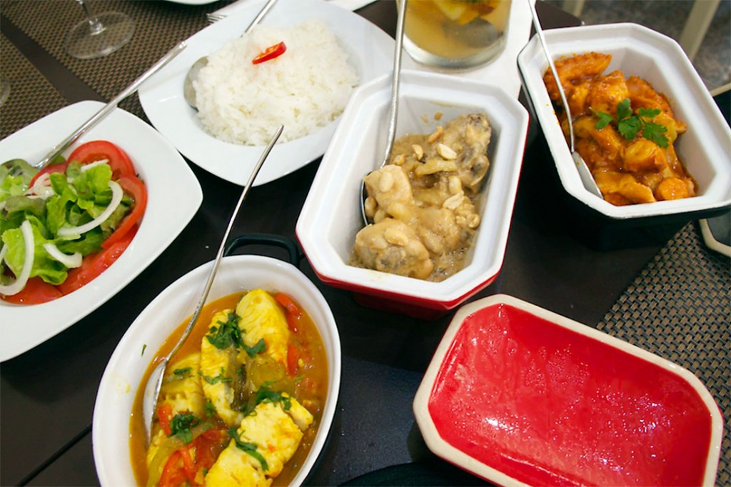 Pratos de frango de amendoim, abacate com atum e moqueca de peixe, acompanhados por arroz, no restaurante língua