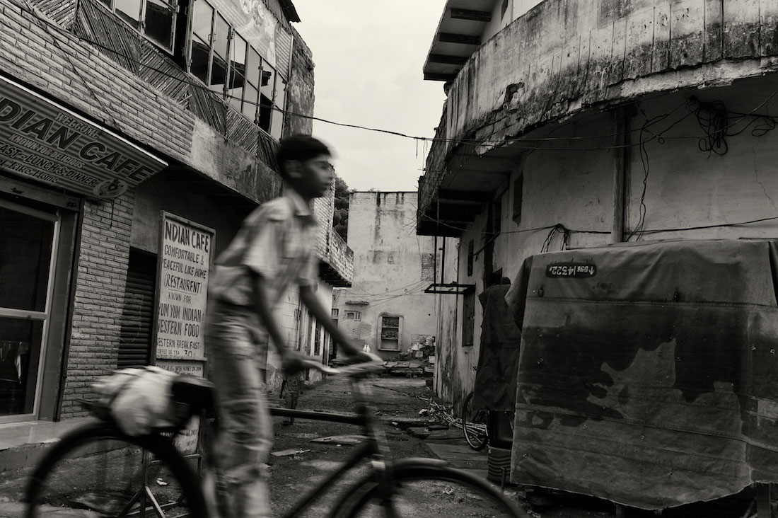 Rapaz a conduzir uma bicicleta numa rua de Agra.