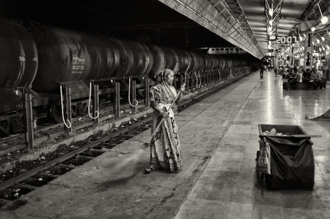 Senhora a varrer o chão do cais na estação de comboios de Agra na Índia.