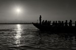 Silhueta de um barco cheio de turistas indianos, no rio Ganges, ao nascer do Sol.
