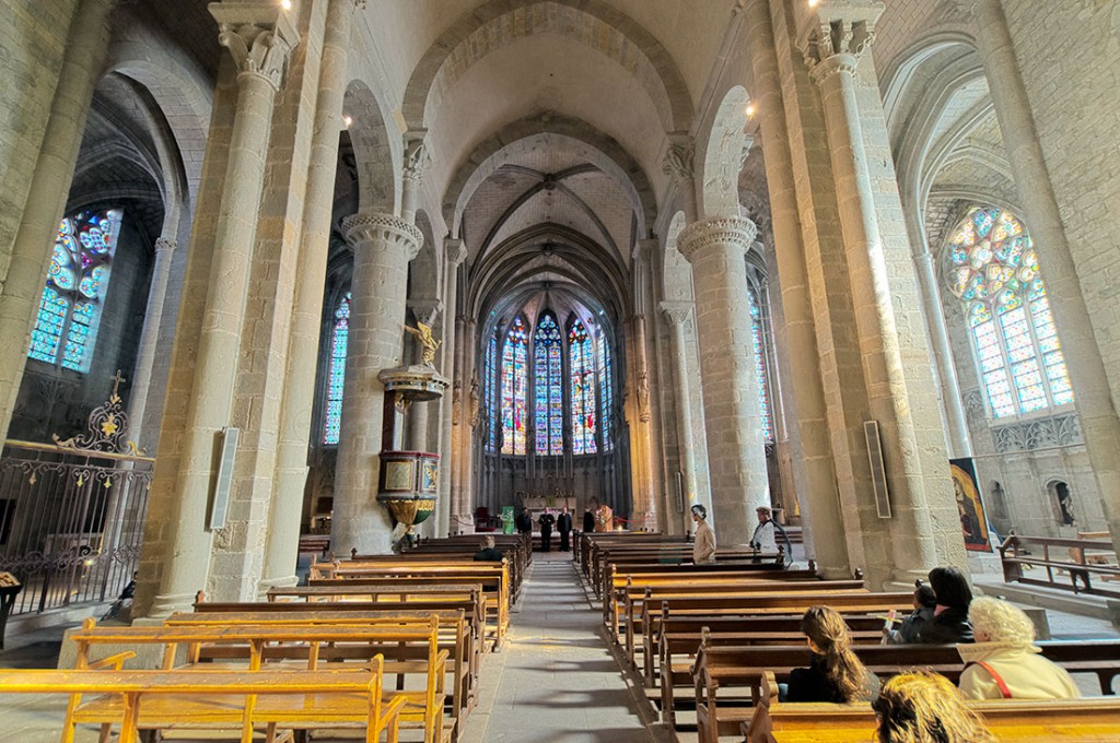 Pessoas sentadas na nave central da basílica de Saint-Nazaire e Saint-Celse em Carcassonne.