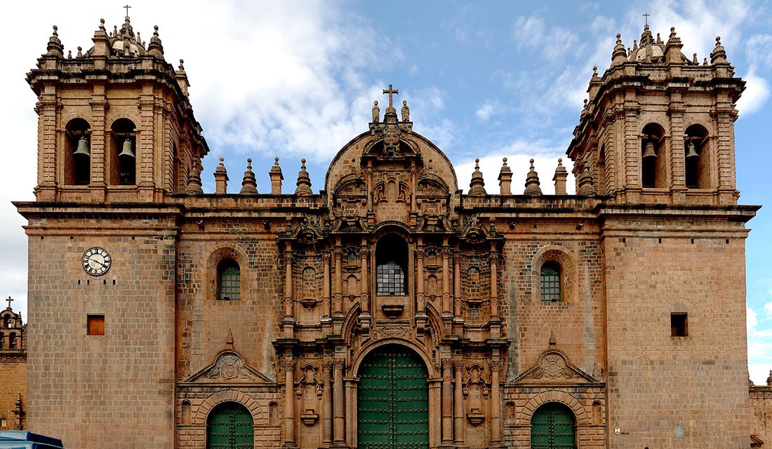 Catedral em pedra alaranjada com duas torres sineiras em Cuzco