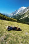Envolvente do Monte Branco com montanhista a descansar sobre a relva de uma colina.