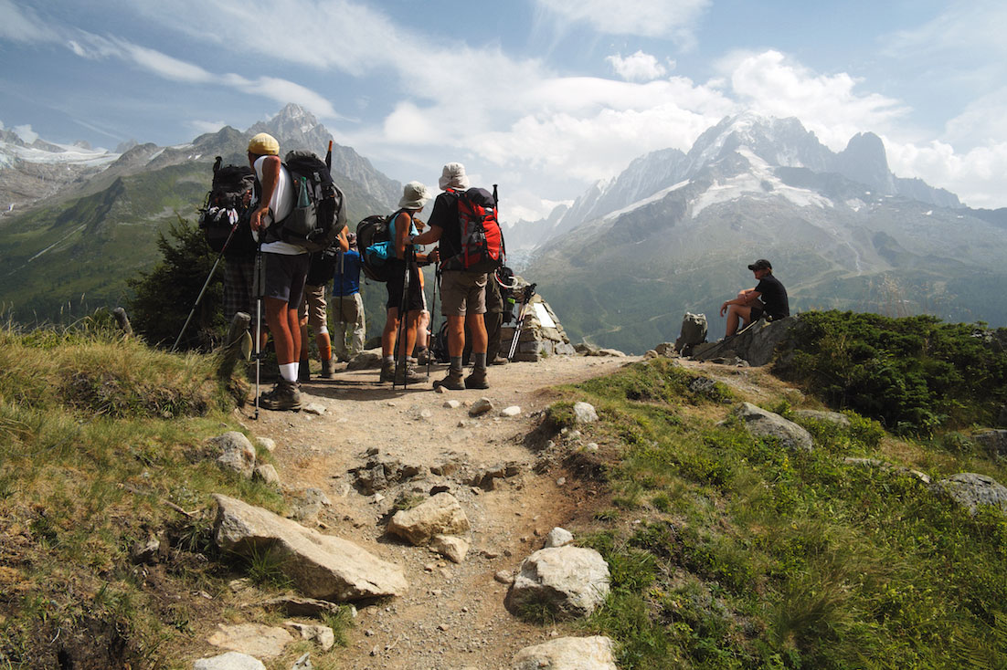 Grupo de montanhistas observa o Maciço do Monte Branco junto a um vale.
