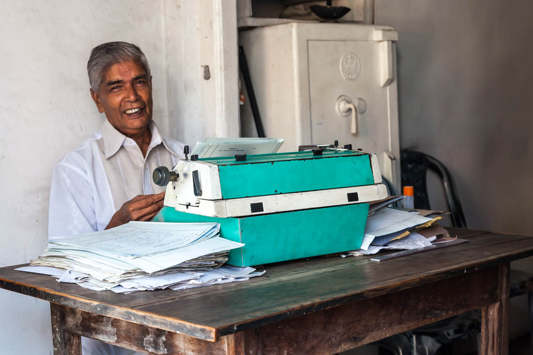 Homem frente a uma máquina de escrever muito antiga num escritório de Tangalle no Sri Lanka.