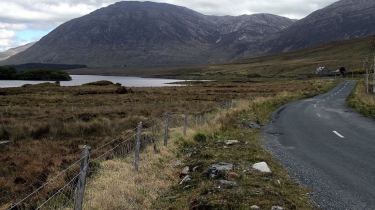 Estrada sinuosa junto a um lago e montanhas no parque nacional de conemara na Irlanda.