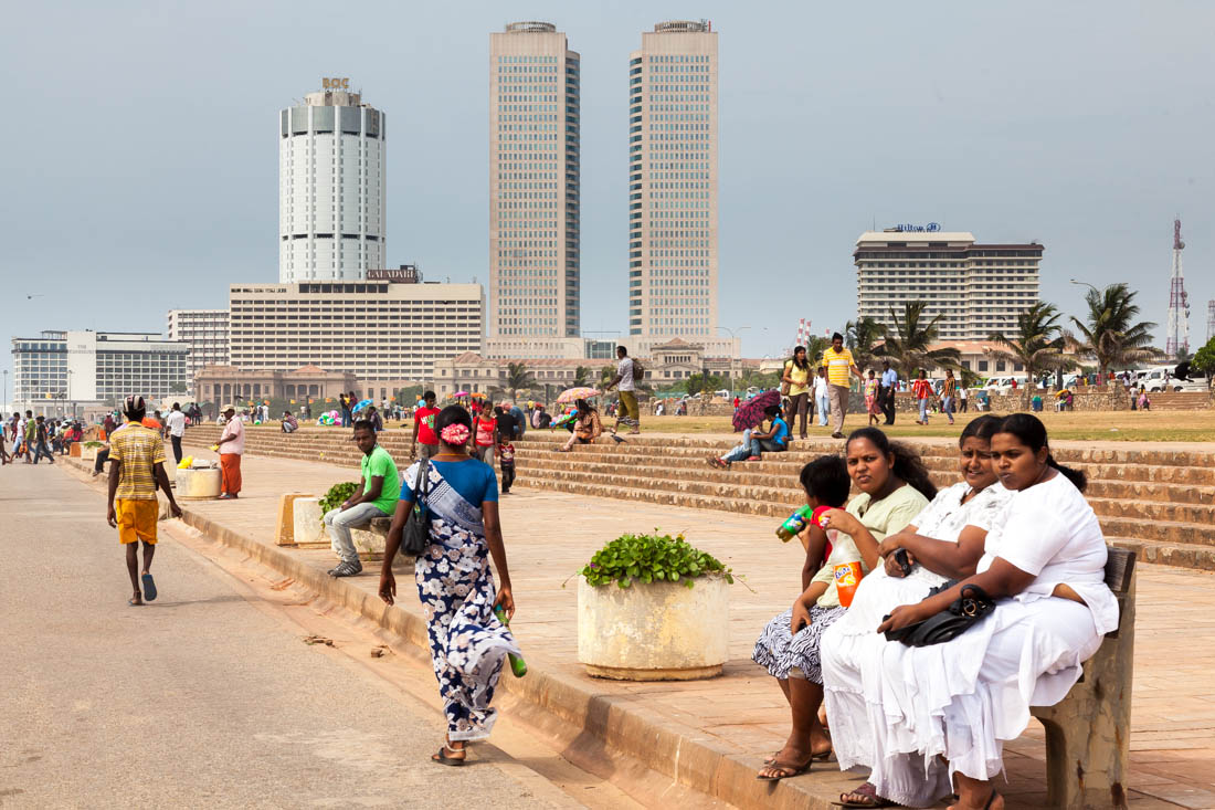 Pessoas sentadas na principal avenida junto ao mar em Colombo, a Galle Face.