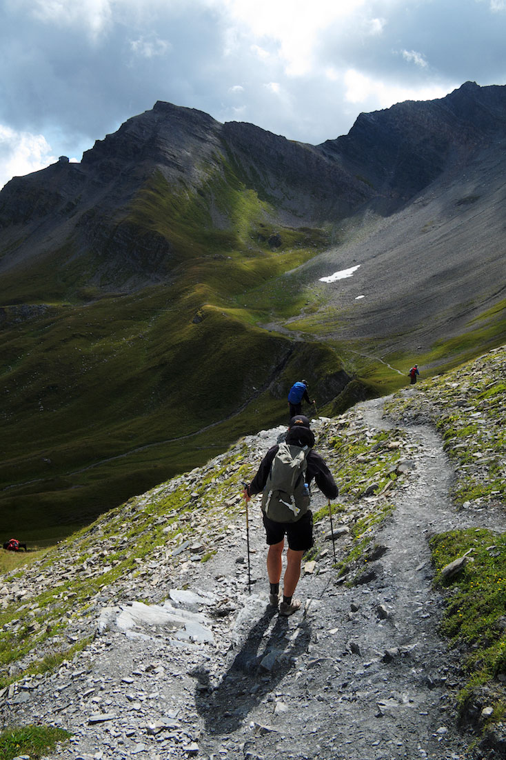 Vários montanhistas descem trilho numa colina acentuada no maciço do monte branco.