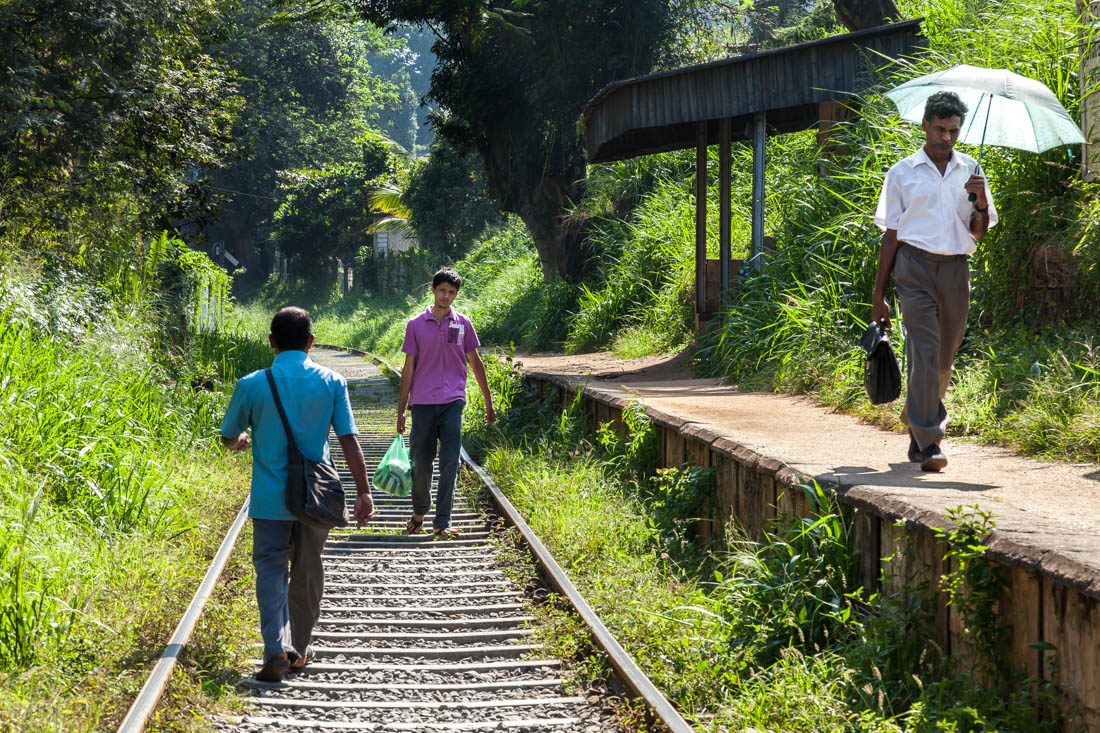 Pessoas a caminhar sobre a linha de caminho-de-ferro numa zona da cidade de Kandy, Sri Lanka.