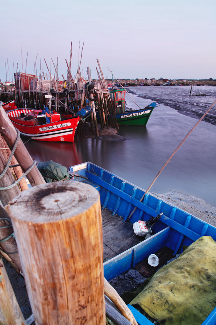 Barcos de pesca, redes, estacas e pontões desorganizados formam o Cais Palafítico da Carrasqueira.