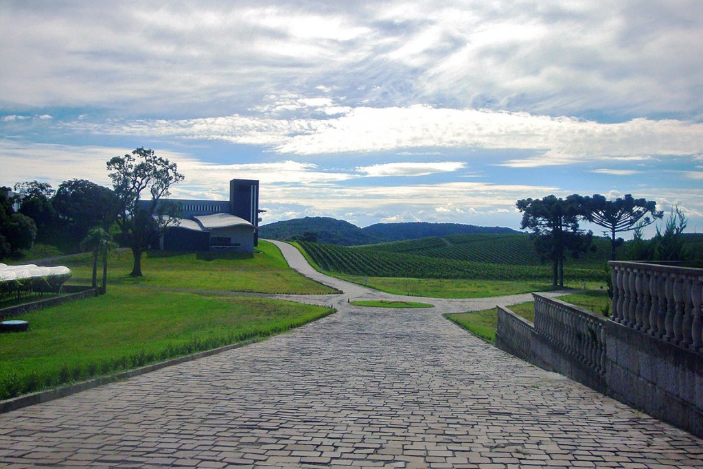 Estrada em pedra basáltica e campos verdes na vinícola Luiz Argenta, em Flores da Cunha, Brasil.