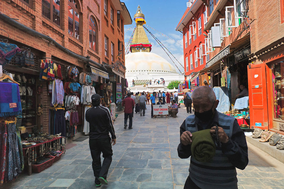 Olhos de Buda no topo da Boudhanath Stupa, desde uma rua com lojas de artesanato.