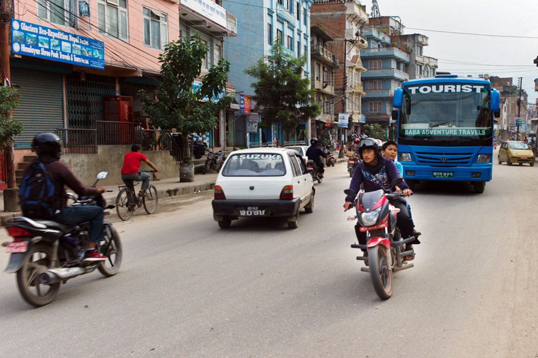 Rapazes aceleram numa moto a grande velocidade por entre o transito de Kathmandu.