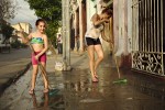 Mãe e filha em limpezas, num passeio de cimento molhado, na cidade cubana de Cienfuegos.
