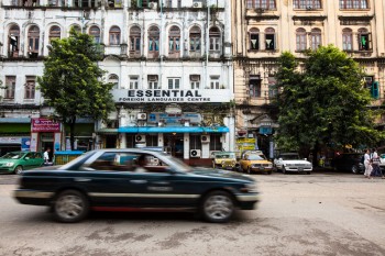 Carro a passar na baixa de Yangon, zona ainda muito marcada pela traça colonial dos edifícios.