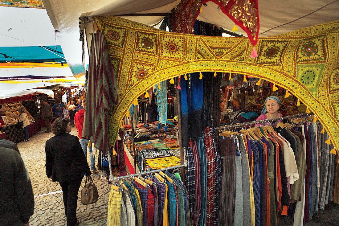 Pessoas a observar roupas numa banca no Festival Islâmico de Mértola.