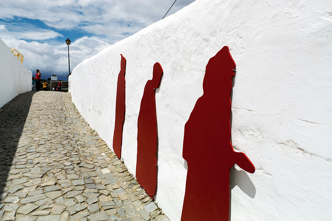 Parede branca com silhuetas vermelhas de mouros numa das ruas típicas de Mértola durante o festival islâmico.