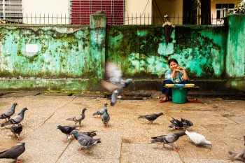 Vendedora de comida para pombos nas ruas de Yangon.