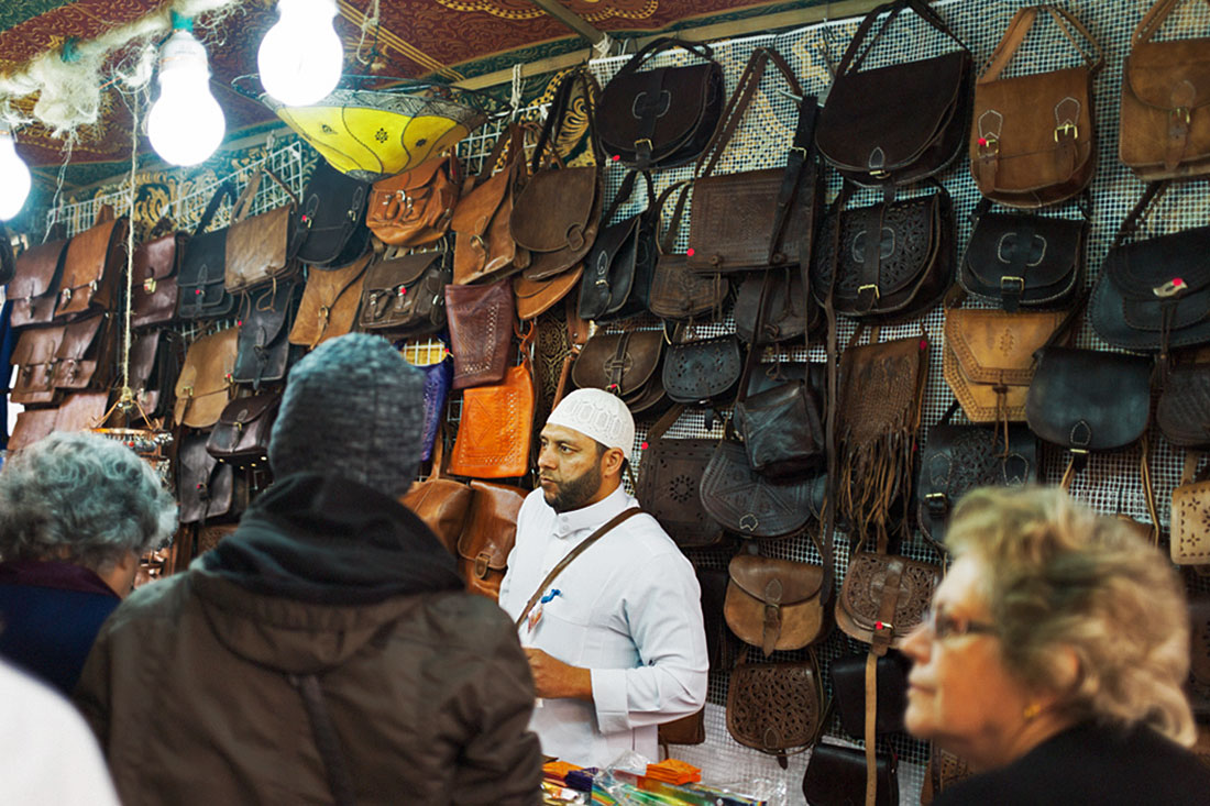 Clientes interessados na marroquinaria de um vendedor marroquino no Festival Islâmico de Mértola.