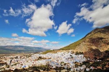 Cidade de Chefchaouen no sopé da montanha debaixo de um céu azul.